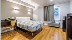 A hotel room with a bed, a desk, a chair, a heater, and a window with curtains. - 1 Queen Bed|Nsmk,Micfridge (Auburn)
