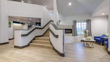 Un interior moderno con una escalera, una chimenea y un área de descanso.