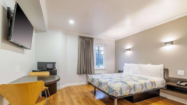 A hotel room with a bed, a desk, a chair, a television, and a window. - 1 Queen Bed|Nsmk,Micfridge (Auburn)