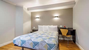 A bedroom with a bed, a desk, a chair, and two wall-mounted lights.