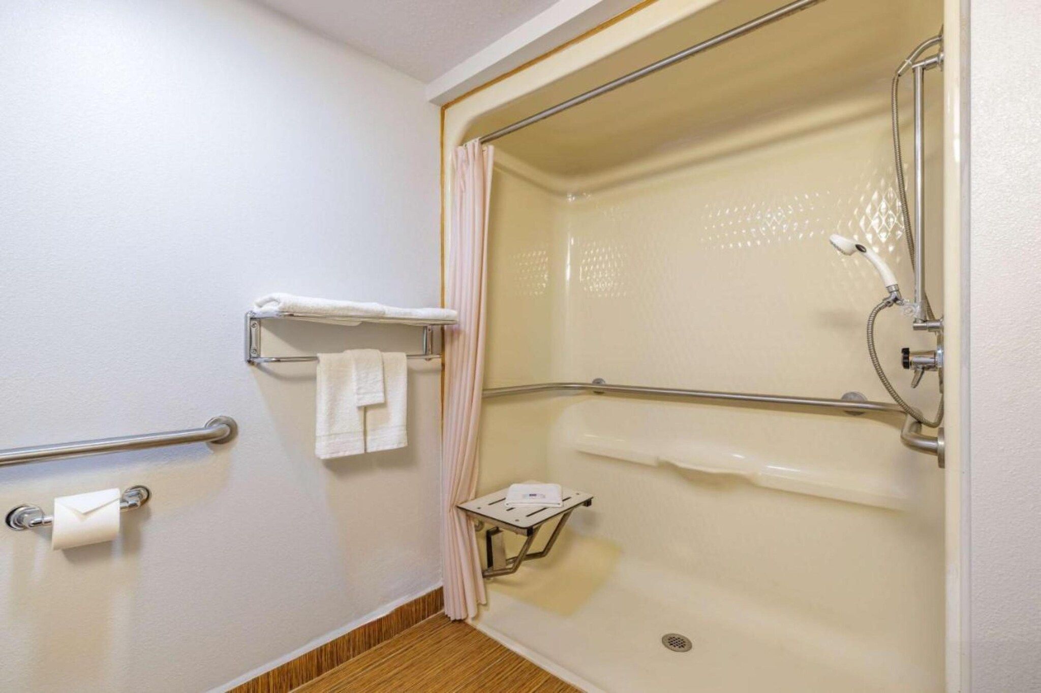Ein Badezimmer mit Dusche, Handtuchhalter, einem kleinen Tisch und einem Toilettenpapierhalter.