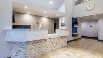 A reception area with a marble counter, a clock, and a stone wall.