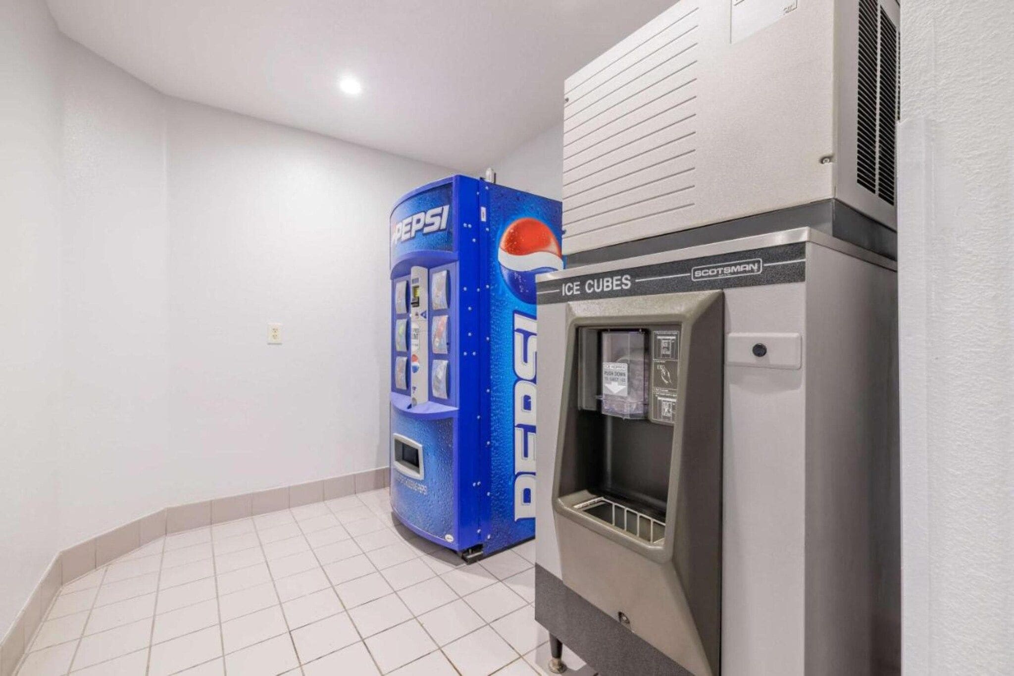 Een toiletruimte met een automaat voor Pepsi en een ijsmachine.