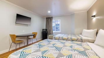 A hotel room with a bed, a desk, a chair, a TV, and a window.