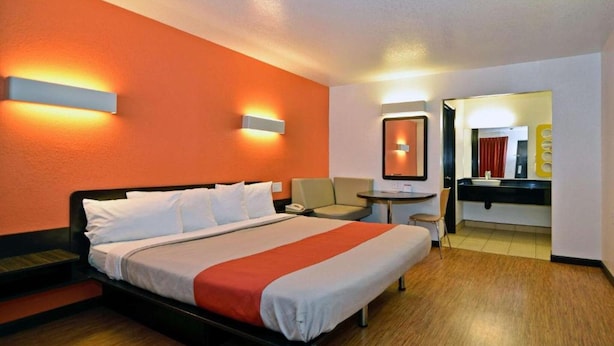 Une chambre d’hôtel avec un lit, une table de chevet et un petit coin salon.