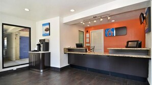 Un espace d’accueil avec un comptoir, une machine à café et une porte donnant sur une autre pièce.