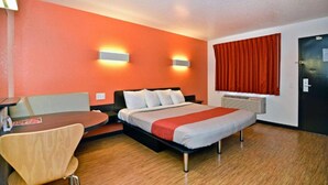 Une chambre d’hôtel avec un lit, un bureau, une chaise et une fenêtre avec des rideaux.