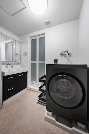 A modern bathroom with a large washing machine, a sink, and a mirror. - E-US Naebo Station 407 (Sapporo)
