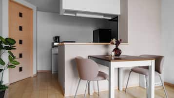 Eine moderne Küche mit einer zentralen Kochinsel, zwei Stühlen, einer Kaffeemaschine und einem Kühlschrank.