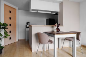 Una cocina moderna con una isla central, dos sillas, una cafetera y un refrigerador.
