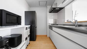 A modern kitchen with white cabinetry, a black refrigerator, a microwave, and a coffee maker.