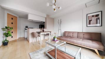 Ein modernes Wohnzimmer mit Sofa, Couchtisch und Essbereich mit Stühlen.