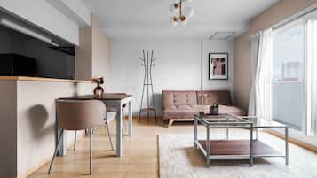 A modern living room with a dining area, a sofa, a coffee table, and a view of the city.
