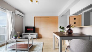 A modern living room with a flat-screen TV, a wooden door, a dining table, and a sofa. - E-US Naebo Station 407 (Sapporo)