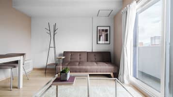 Ein modernes Wohnzimmer mit einer Couch, einem Couchtisch, einer Stehlampe und Blick auf die Stadt durch große Fenster.
