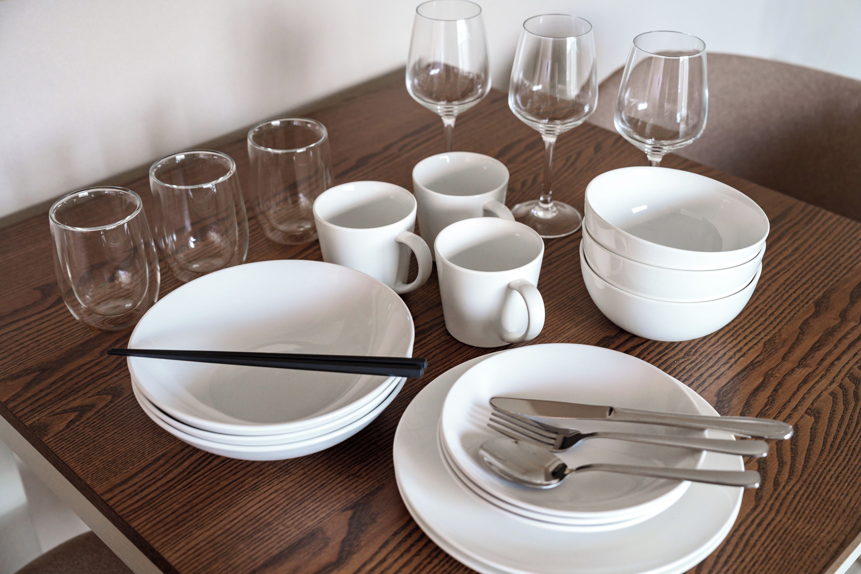 A dining table set with white plates, bowls, cups, and cutlery.