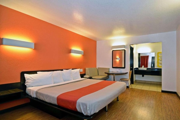 Quarto de hotel com cama, mesa de cabeceira e um pequeno espaço de estar.