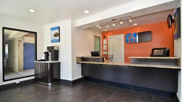 A reception area with a counter, a coffee machine, and a door leading to another room.