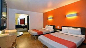 Habitación de hotel con dos camas, un escritorio y un espejo.