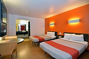Ein Hotelzimmer mit zwei Betten, einem Schreibtisch und einem Spiegel.