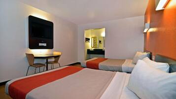 Habitación de hotel con dos camas, un escritorio y televisor.