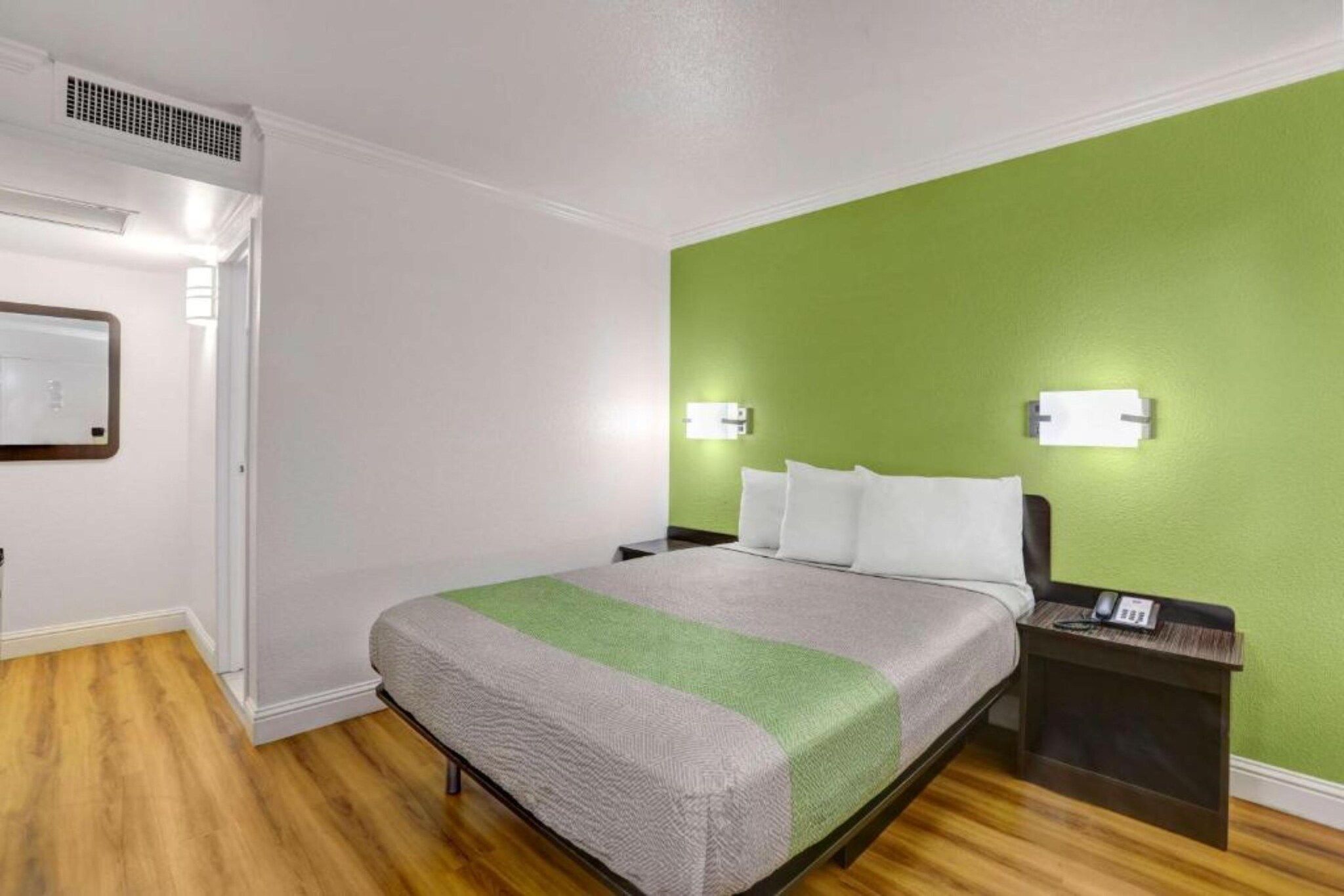Een hotelkamer met een bed, nachtkastje en een groene accentmuur.