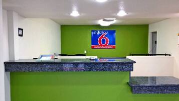 A reception desk with a green wall and a sign that reads 'studio 6 extended stay.'