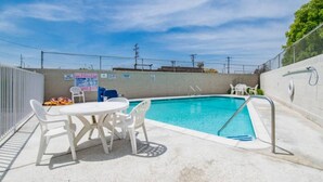 A swimming pool with a table and chairs, surrounded by a fence and signs. - 1 King Bed|Mobil Access Tub NS Kitchen (Cypress)
