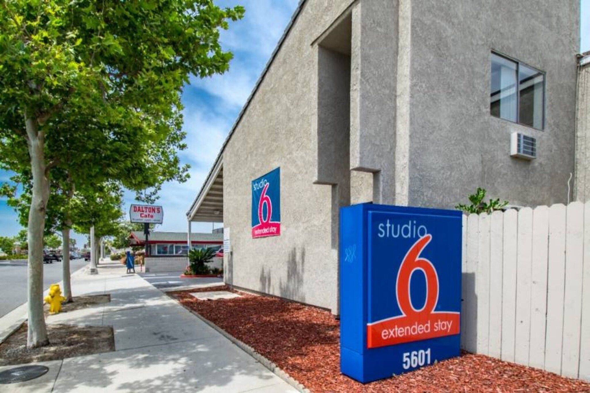 A building with a sign for 'Studio 6 Extended Stay' and a 'Dalton's Cafe' sign in the background.