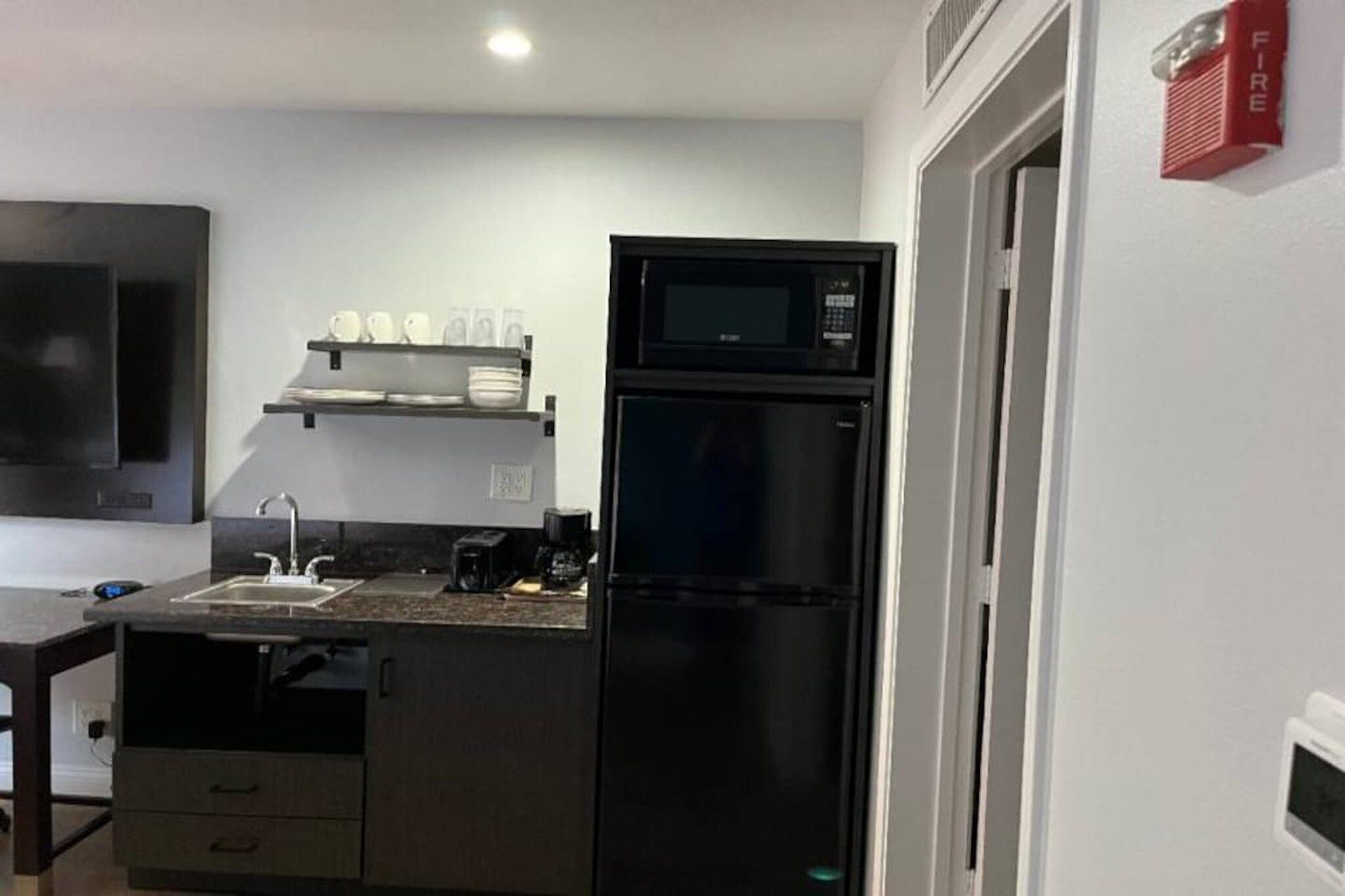 A compact kitchen with a refrigerator, microwave, and a coffee maker.