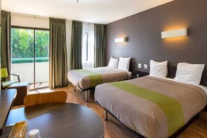 Een hotelkamer met twee bedden, een bureau en een stoel.