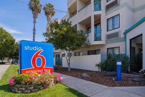A sign for Studio 6 Extended Stay hotel with a modern building in the background.