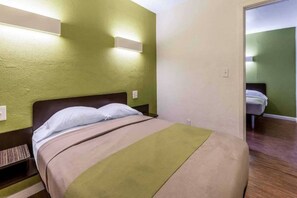 A hotel room with a bed, a nightstand, and a wall-mounted light fixture. - 1 King Bed | Non-Smoking (San Rafael)
