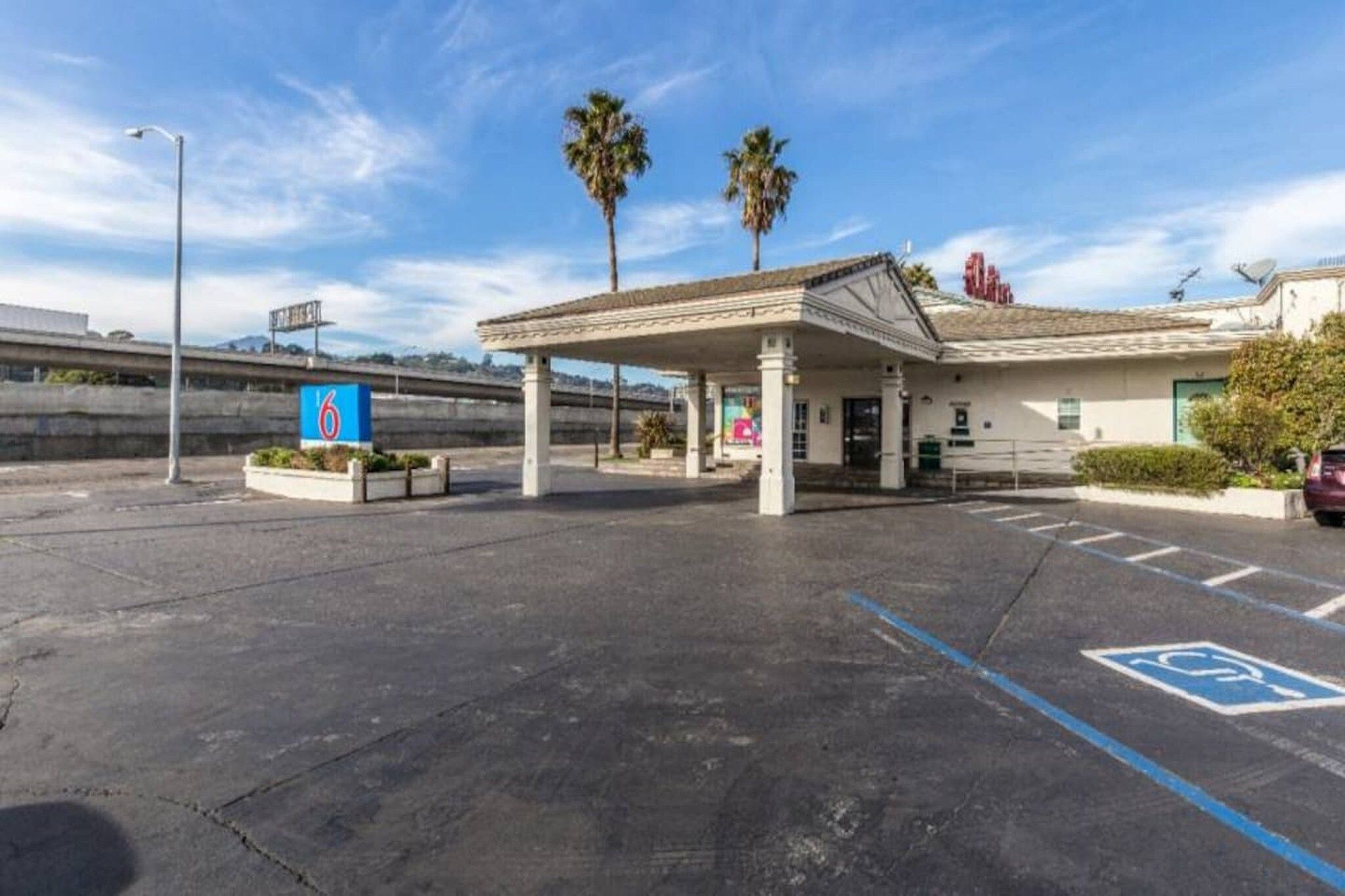 A gas station with a canopy, a handicap parking sign, and palm trees in the background.