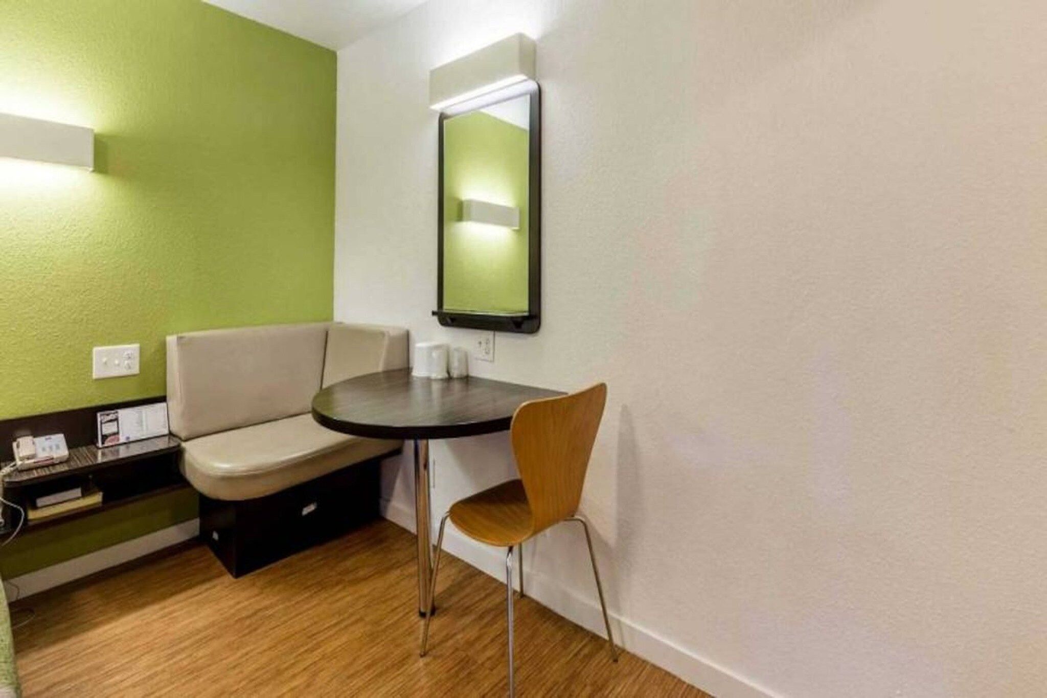 A small room with a round table, two chairs, a bench, and a mirror on the wall.