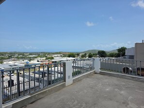 Eine Dachterrasse mit Metallgeländer, Blick auf eine Stadtlandschaft und ein fernes Gebirge.