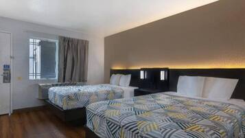 Une chambre d’hôtel avec deux lits, une fenêtre avec des rideaux et un luminaire fixé au mur.