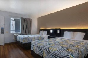 Habitació d'hotel amb dos llits, una finestra amb cortines i una làmpada de paret.