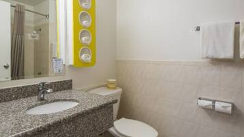 A bathroom with a granite countertop sink, a toilet, and a mirror.