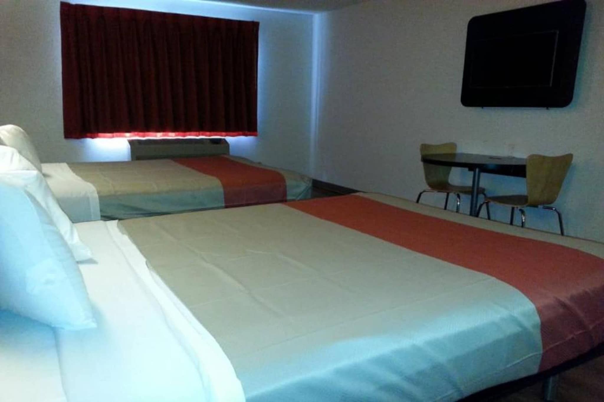 Een hotelkamer met twee bedden, een bureau en een stoel.