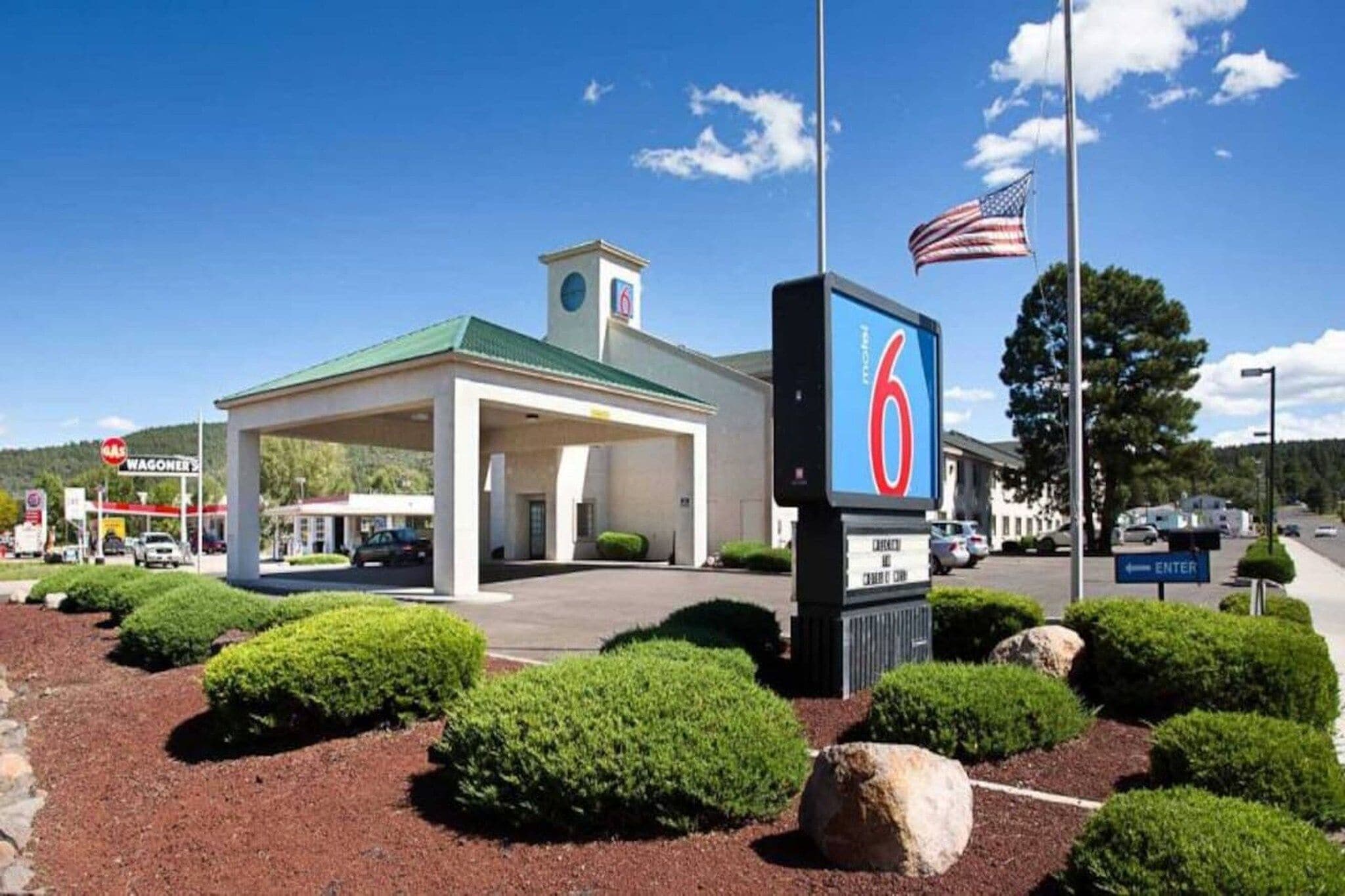 Ein Motel mit einem grünen Dach, einem Fahnenmast mit der US-amerikanischen Flagge und einem Schild mit der Nummer 6.