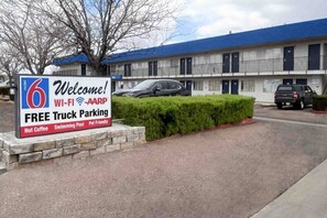 A motel with a sign advertising free truck parking, Wi-Fi, AARP membership, hot coffee, a swimming pool, and pet-friendly accommodations.