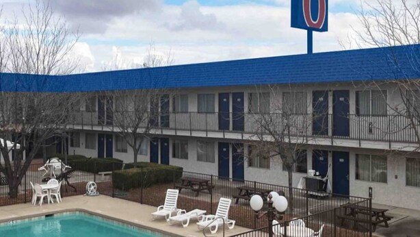 Un motel con piscina, asientos al aire libre y un letrero grande que indica el número 6.