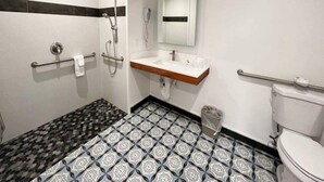 Un baño con lavamanos blanco, espejo, inodoro y ducha.