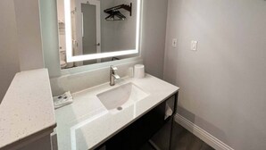 Un baño moderno con un espejo grande, un lavabo y un inodoro visibles en el reflejo.