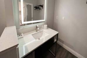 Un bagno moderno con uno specchio grande, un lavandino e un water visibili nel riflesso.
