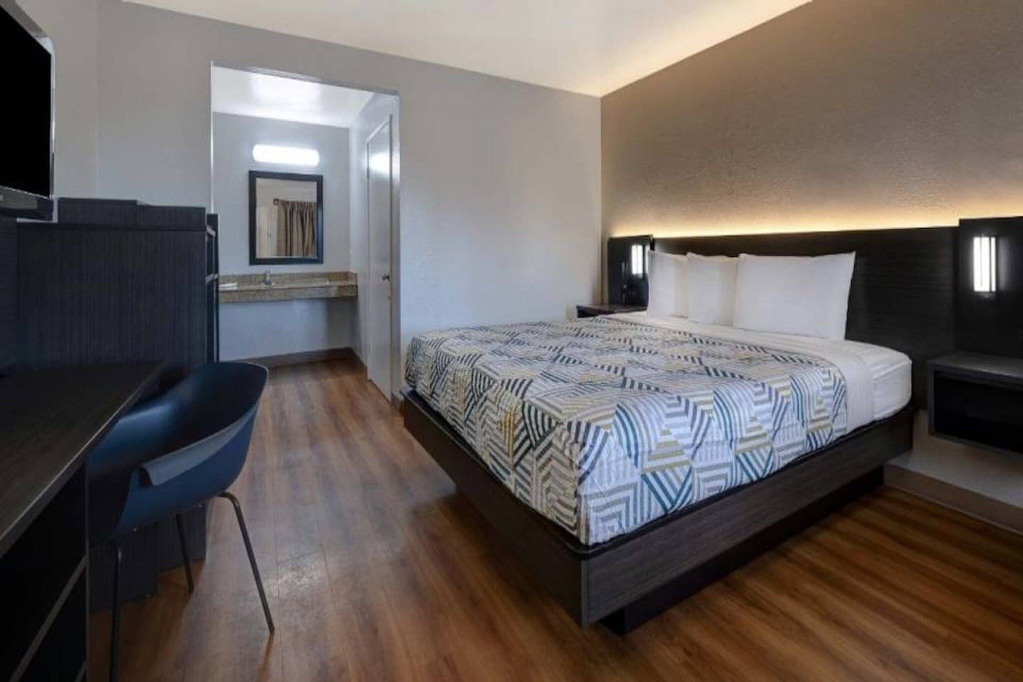 A hotel room with a bed, a desk, and a chair.