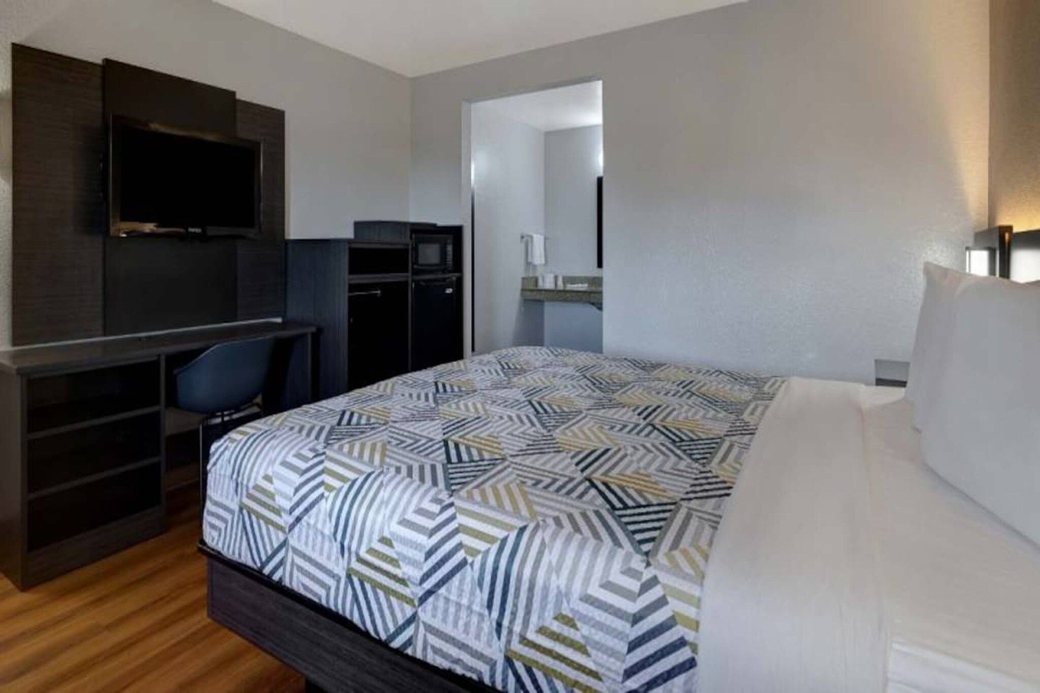 A hotel room with a bed, a desk, a TV, and a wardrobe.