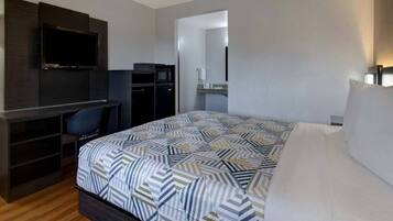 A hotel room with a bed, a desk, a TV, and a wardrobe.