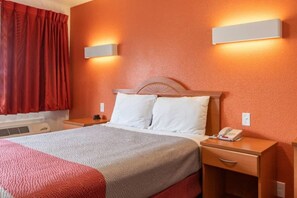 A hotel room with a bed, bedside tables, a telephone, and a window with curtains.